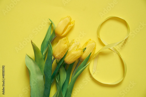 Five yellow fresh tulips on a yellow background. Flowers with the number eight made of ribbon. Concept of holiday, March 8, International womans day. Card with copy space. photo