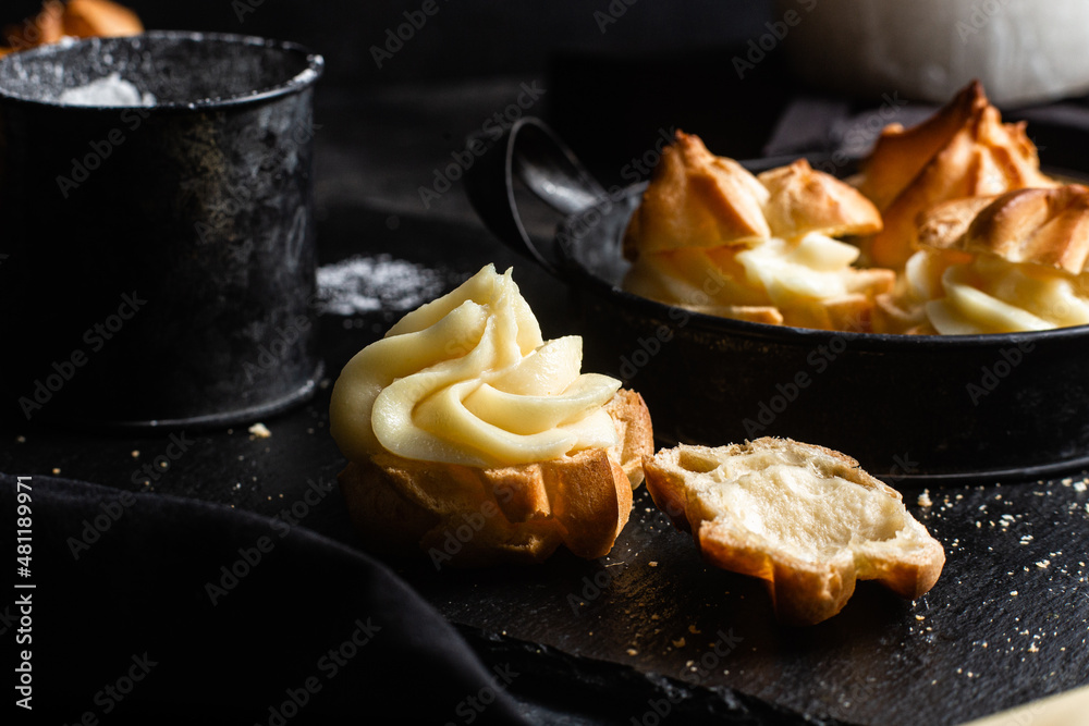 Profiteroles with custard on a dark table. Eclairs Profiteroles with custard on a dark table. Eclairs