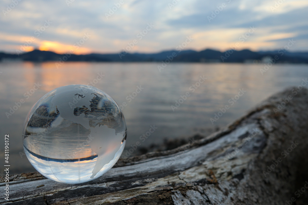 ガラスの地球儀(アメリカ大陸)と夕暮れの湖岸 SDGs 環境保護 イメージ glass globe on the shore of the lake at sunset ガラスの地球儀(アメリカ大陸)と夕暮れの湖岸 SDGs 環境保護 イメージ glass globe on the shore of the lake at sunset