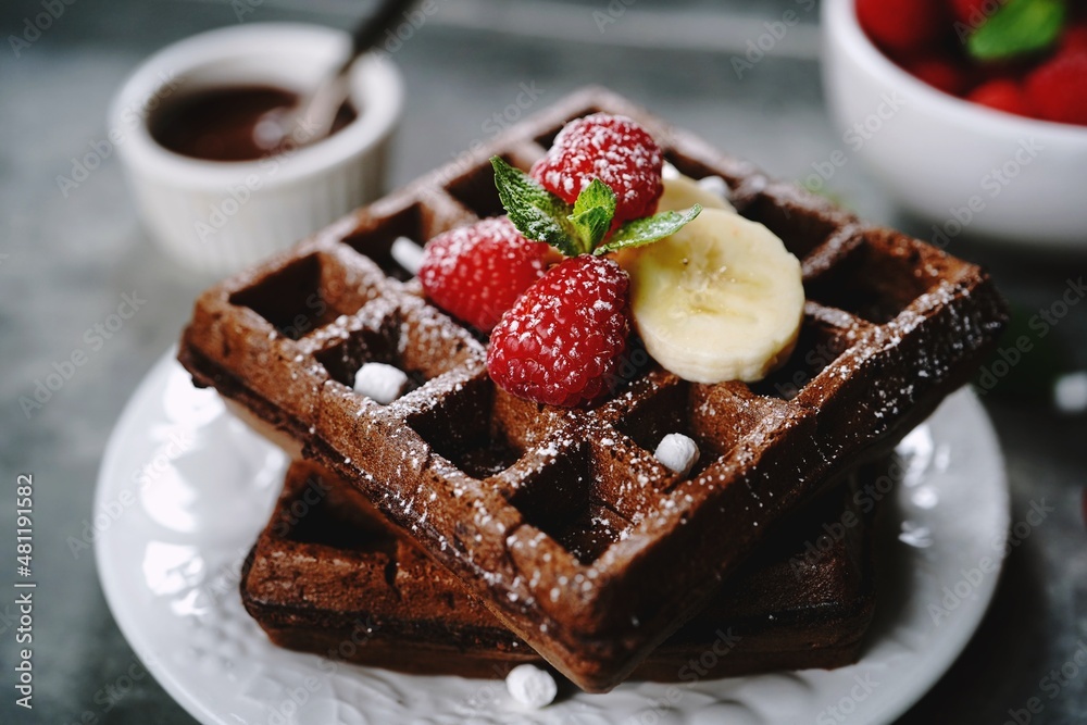 Chocolate square waffles topped with berries and banana, selective focus