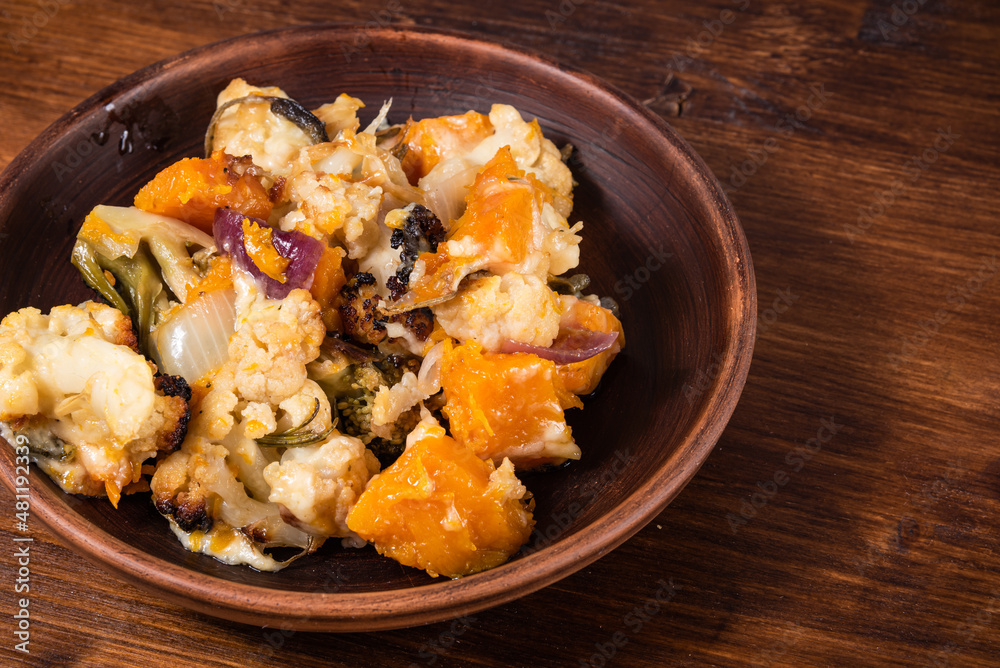 Vegetable stew with broccoli, cauliflower and pumpkin baked with cheese on a plate - healthy mediterranean cuisine Vegetable stew with broccoli, cauliflower and pumpkin baked with cheese on a plate - healthy mediterranean cuisine