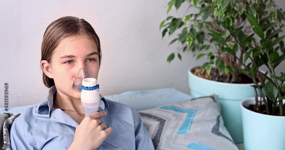 Teenage girl makes inhalation with a nebulizer equipment. Sick child holding inhalator in hand and breathes through an inhaler at home. Physical therapy for cold, flu and bronchial asthma Teenage girl makes inhalation with a nebulizer equipment. Sick child holding inhalator in hand and breathes through an inhaler at home. Physical therapy for cold, flu and bronchial asthma