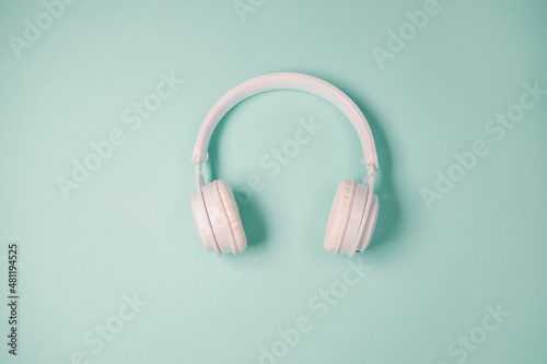 Studio shot of modern white wireless headphones isolated on green mint background. Music concept with copyspace