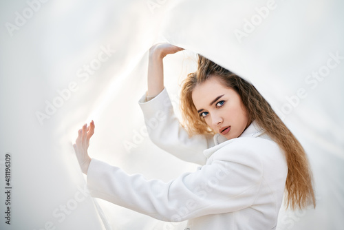 Young attractive woman in white clothes posing on abstract pale background looking at camera confident