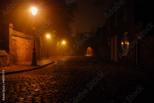 Valokuvatapetti Illuminated cobbled street in an old town with light reflections on cobblestones