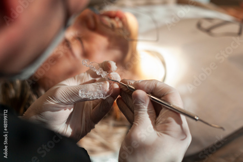 Close-up of an orthodontic specialist holding an invisible aligner in his hand. Concept of invisible orthodontic technique.