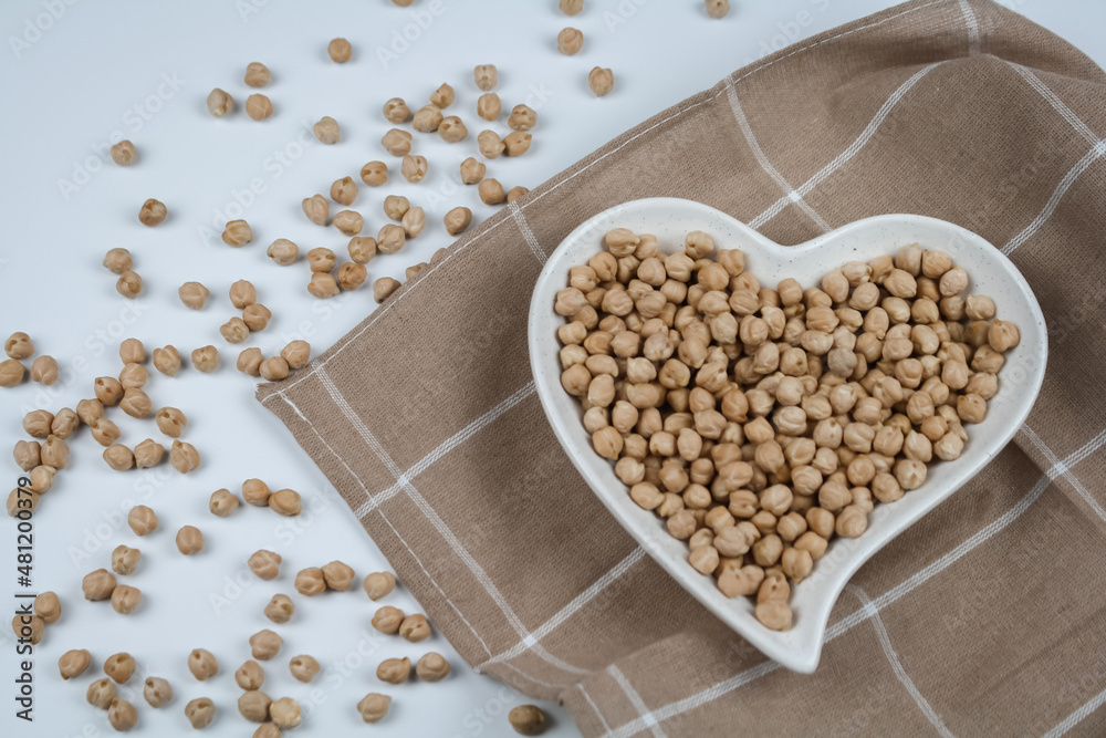 Raw chickpeas on the heart shaped plate and towel. Top view. Raw chickpeas on the heart shaped plate and towel. Top view.