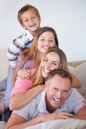 Tiers of management. Portrait of a happy young family of four piled on top of one another.