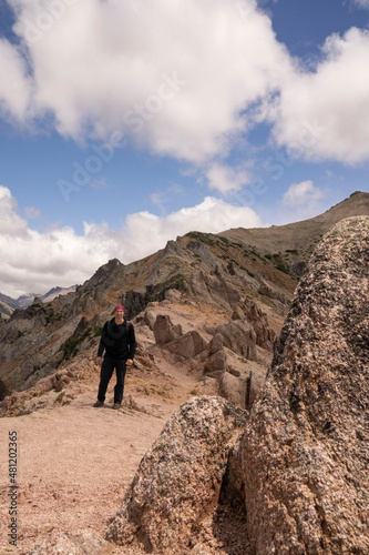 Hiking in the top of the mountain. Portrait of a young man trekking along the Bella Vista hill rocky peak in Bariloche, Patagonia Argentina. 