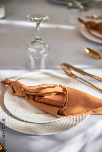 Table setting with sparkling wineglasses, plate with brown napkin and cutlery on table, copy space. Place set at wedding reception. Table served for wedding banquet in restaurant
