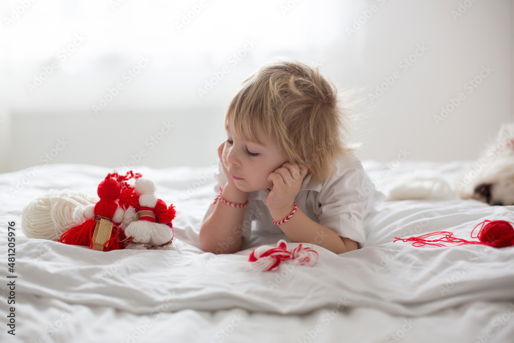 Cute child, blond boy, playing with white and red bracelet Cute child, blond boy, playing with white and red bracelet