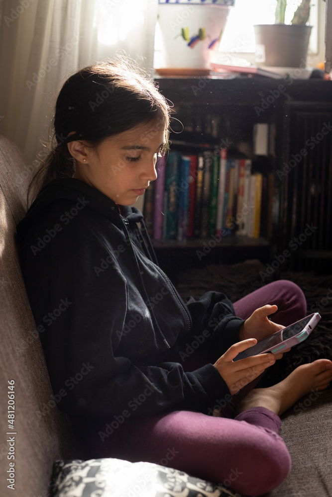 Ethnic girl browsing smartphone on couch
