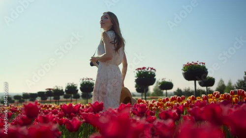 Beautiful girl with camera walking through tulip field. Woman smiling in garden. photo