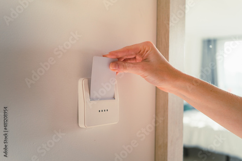 Crop lady inserting card key into switch in hotel room