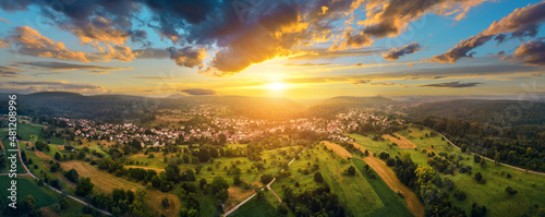 Aerial panoramic landscape with a small town at a dramatic colorful sunset with blue sky and gold clouds