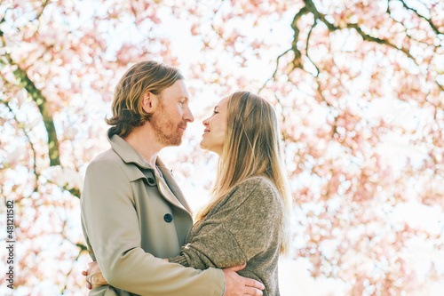Happy romantic couple posing under blooming tree