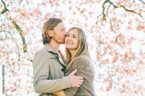 Happy romantic couple kissing under blooming tree