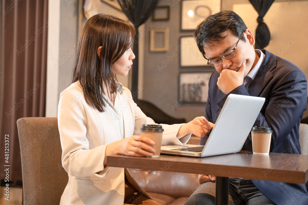 Obraz premium カフェでパソコンで打ち合わせをする男女のビジネスマン