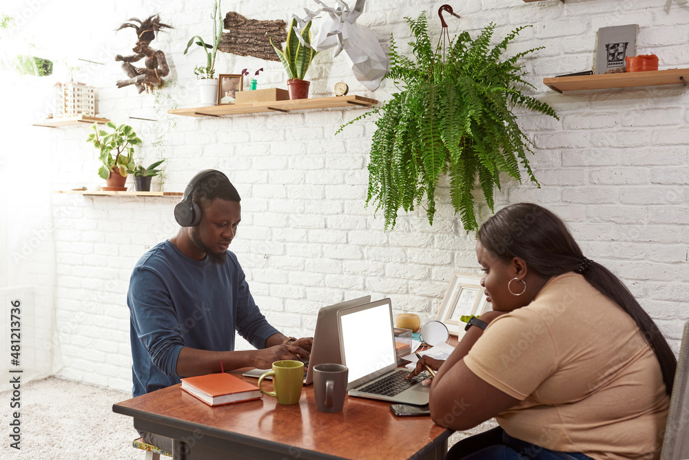 Black man and woman typing and watching on laptops Black man and woman typing and watching on laptops
