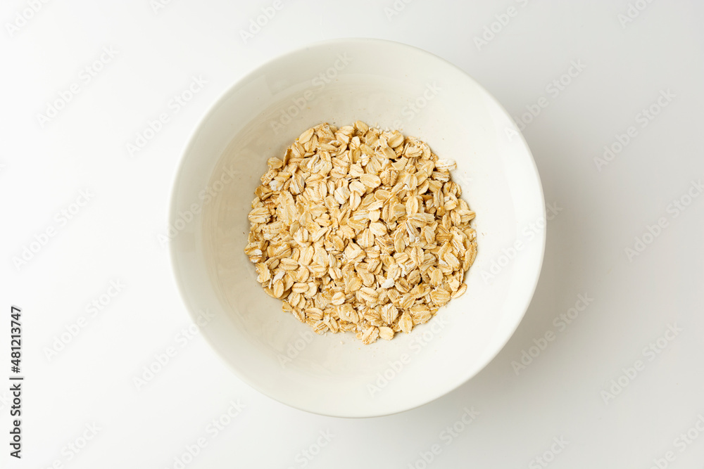Rolled oats in a bowl on white background, top view Rolled oats in a bowl on white background, top view