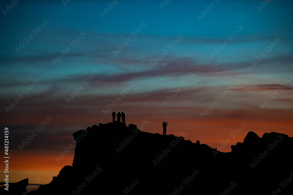 silhouettes on the top of a moutain. Beautiful colors sunset with blues, reds and magentas. 
