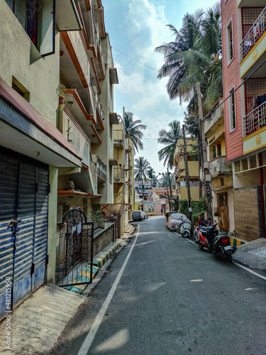 Stock photo of residential area in bangalore city, cluster of apartment buildings and houses, parked vehicles, empty asphalt alley in th city.Picture captured under bright sunlight . selective focus.