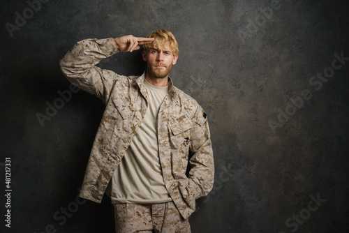 White military man wearing uniform saluting and looking at camera