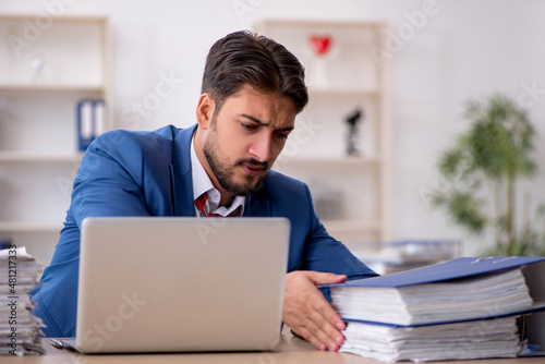 Young male employee and too much work in the office