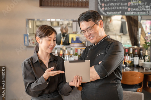 飲食店でタブレットPCで相談する男女の店員