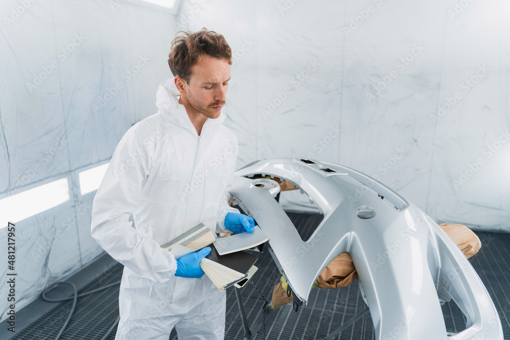 Auto painter works with samples of car paint colors in the automobile painting booth Auto painter works with samples of car paint colors in the automobile painting booth