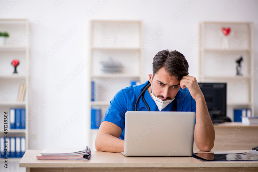 Young male doctor working in the clinic during pandemic Young male doctor working in the clinic during pandemic