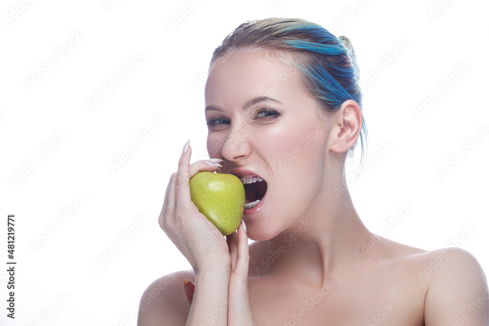 Agressive Caucasian Female with Teeth Braces and Smooth Skin Posing With Green Apple As Dental Care Ideas Against White. Agressive Caucasian Female with Teeth Braces and Smooth Skin Posing With Green Apple As Dental Care Ideas Against White.