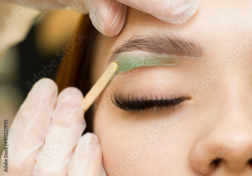 Workshop wax depilation of eyebrow hair in women, eyebrow correction. Green wax © Ксенич Шитовкина