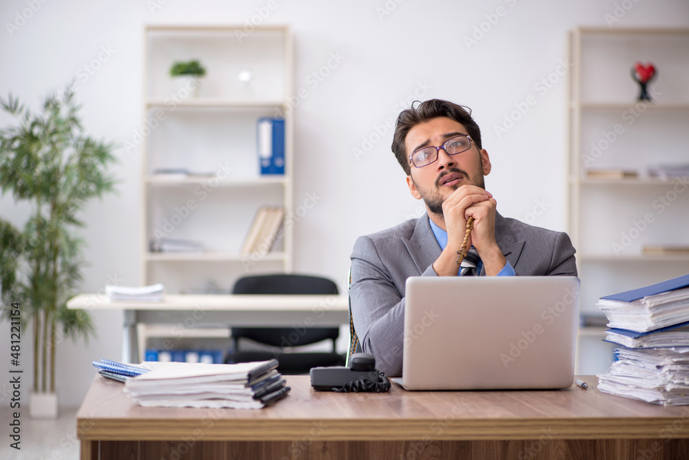 Young male employee unhappy with excessive work in the office Young male employee unhappy with excessive work in the office