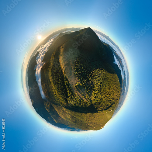 Fototapeta Naklejka Na Ścianę i Meble -  Aerial view from high altitude of little planet earth at sunrise covered with evergreen forest and high mountain peaks
