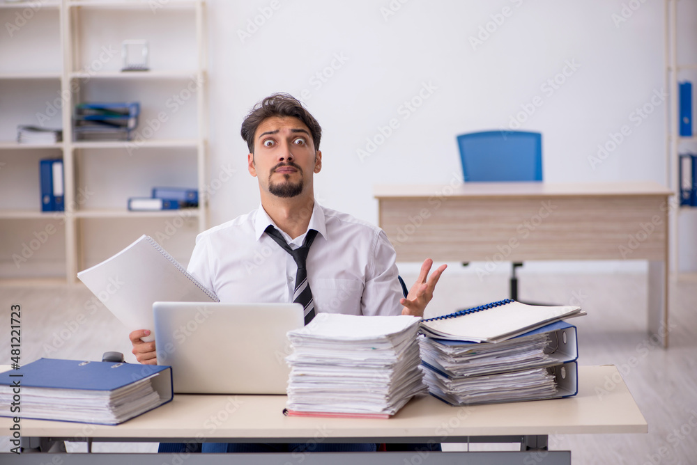 Obraz premium Young male employee and too much work in the office