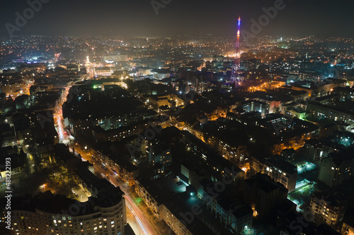Aerial view of high rise apartment buildings and bright illuminated streets in Ivano-Frankivsk city, Ukraine residential area at night. Dark urban landscape