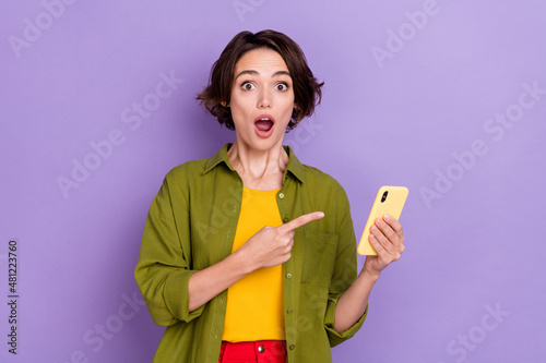 Photo of young astonished lady indicate finger mobile comment decision 4g isolated over violet color background