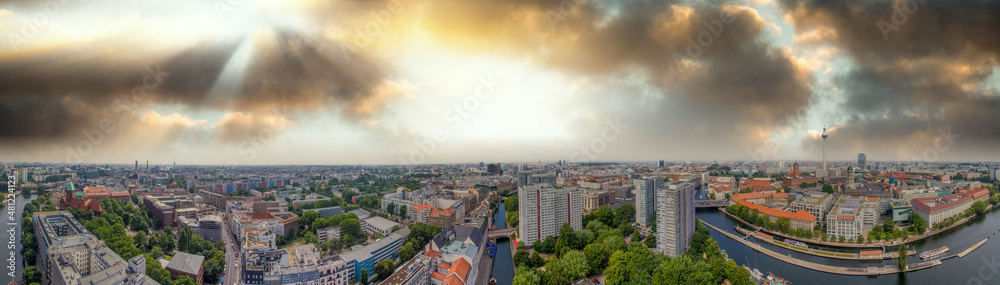 Panoramic aerial view of Berlin skyline at sunset with major city landmarks along Spree river, Germany from drone in summer season.