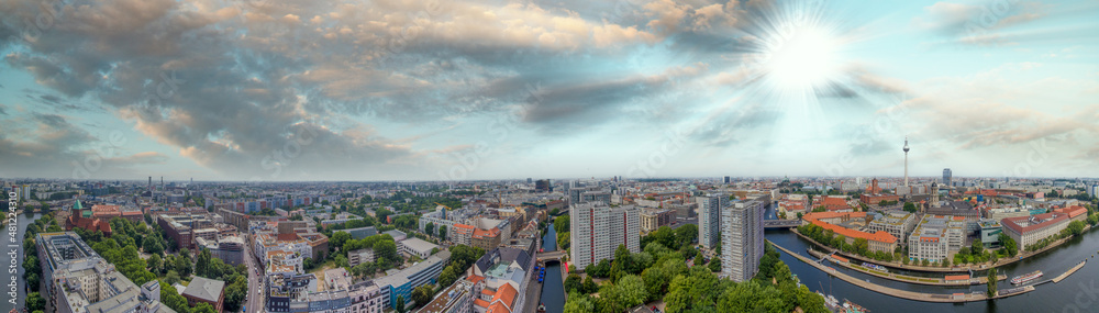 Panoramic aerial view of Berlin skyline at sunset with major city landmarks along Spree river, Germany from drone in summer season.