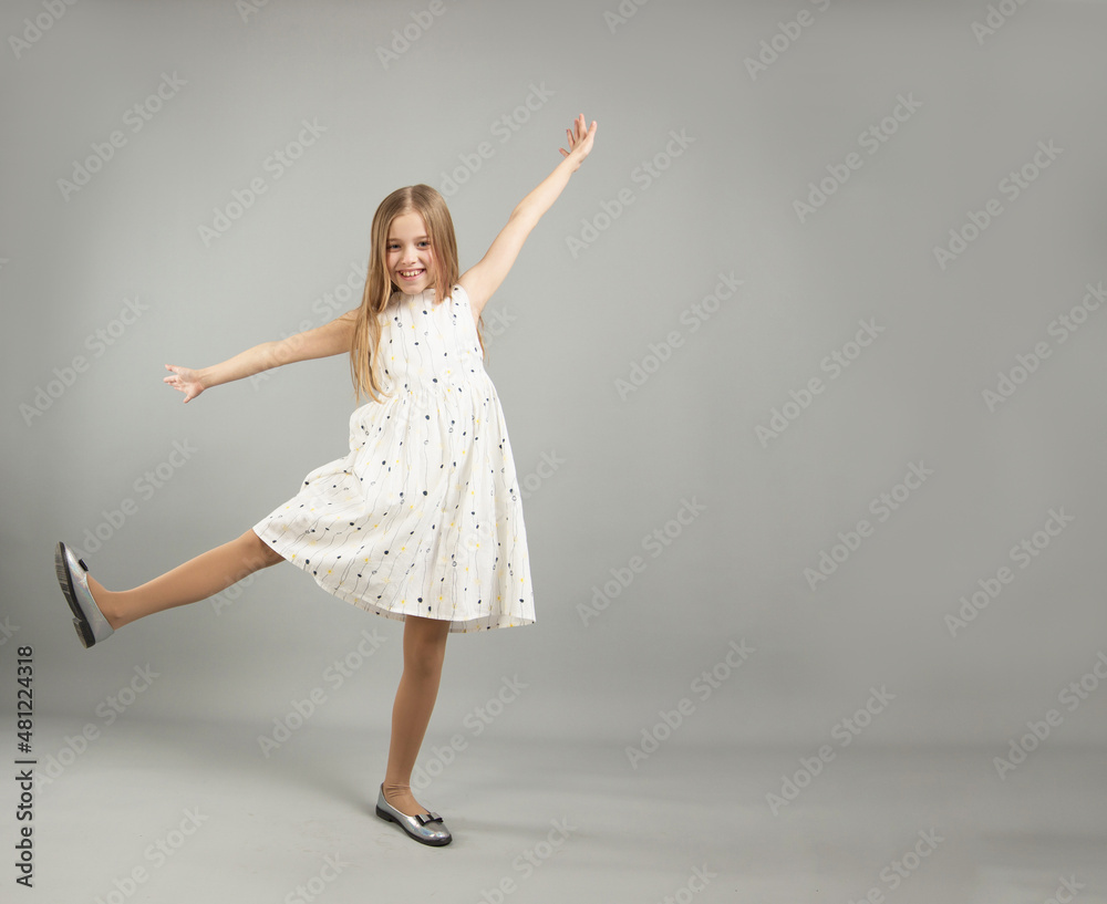 Naklejka premium the concept of happiness, freedom, power, movement and people - a smiling young girl jumps in the air on a gray background
