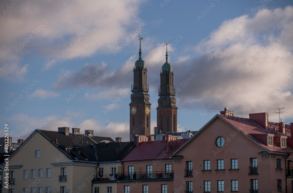 Roofs and facades of old 1800s buildings and the twin towers of the church Högalidskyrkan a sunny day in Stockholm