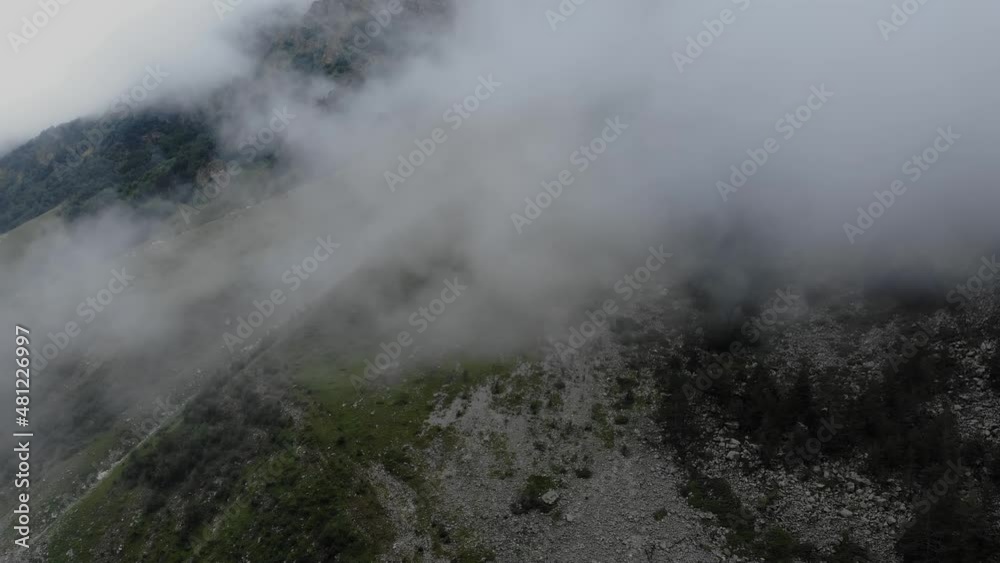 Stunning aerial views of the steep slopes and peaks of the Caucasus Mountains covered with low clouds. Drone flight in the forest between the treetops. Tourist destinations and routes in the Caucasus. Stunning aerial views of the steep slopes and peaks of the Caucasus Mountains covered with low clouds. Drone flight in the forest between the treetops. Tourist destinations and routes in the Caucasus.
