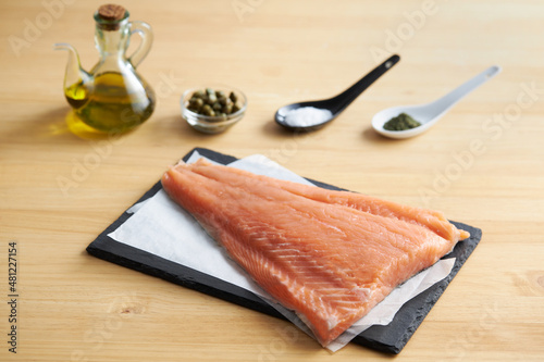 Raw fish on cutting slate board with ingredients