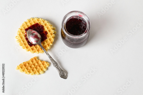 Crunchy cookies, waffles or snacks and a little pot of jam on a solid white background. Copy space, isolate, top view