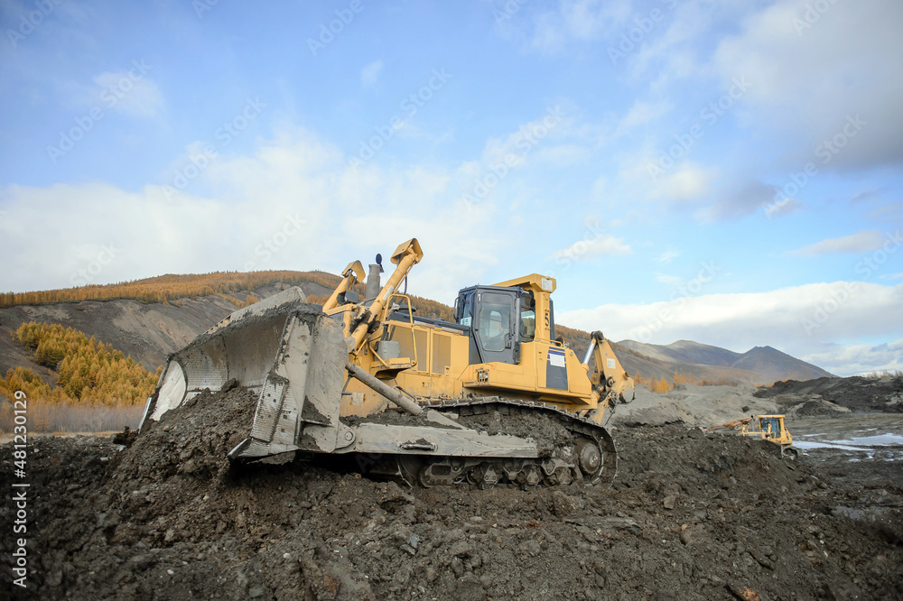 A bulldozer works at a gold mining site. A bulldozer works at a gold mining site.