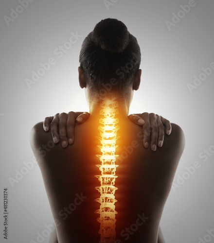 Targeting the pain. Rearview shot of a woman holding her back in pain. photo