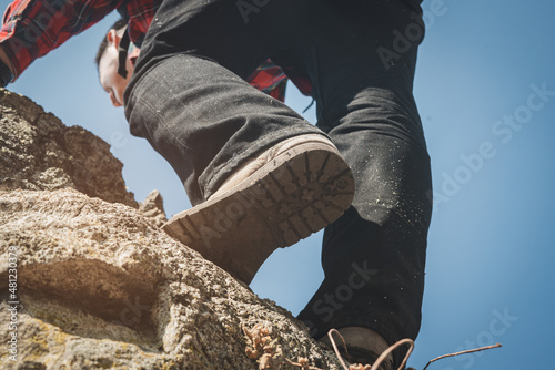 Man hiker steps on the mountain trail on the rocks