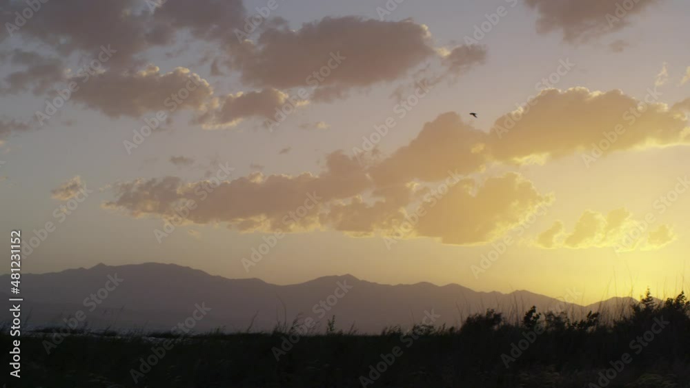 Sunset on lake with marsh grasses and mountains in the distance at Utah Lake Sunset on lake with marsh grasses and mountains in the distance at Utah Lake
