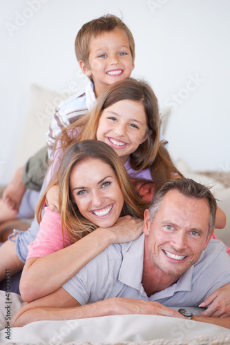 Family is all about balance. Portrait of a happy young family of four piled on top of one another.